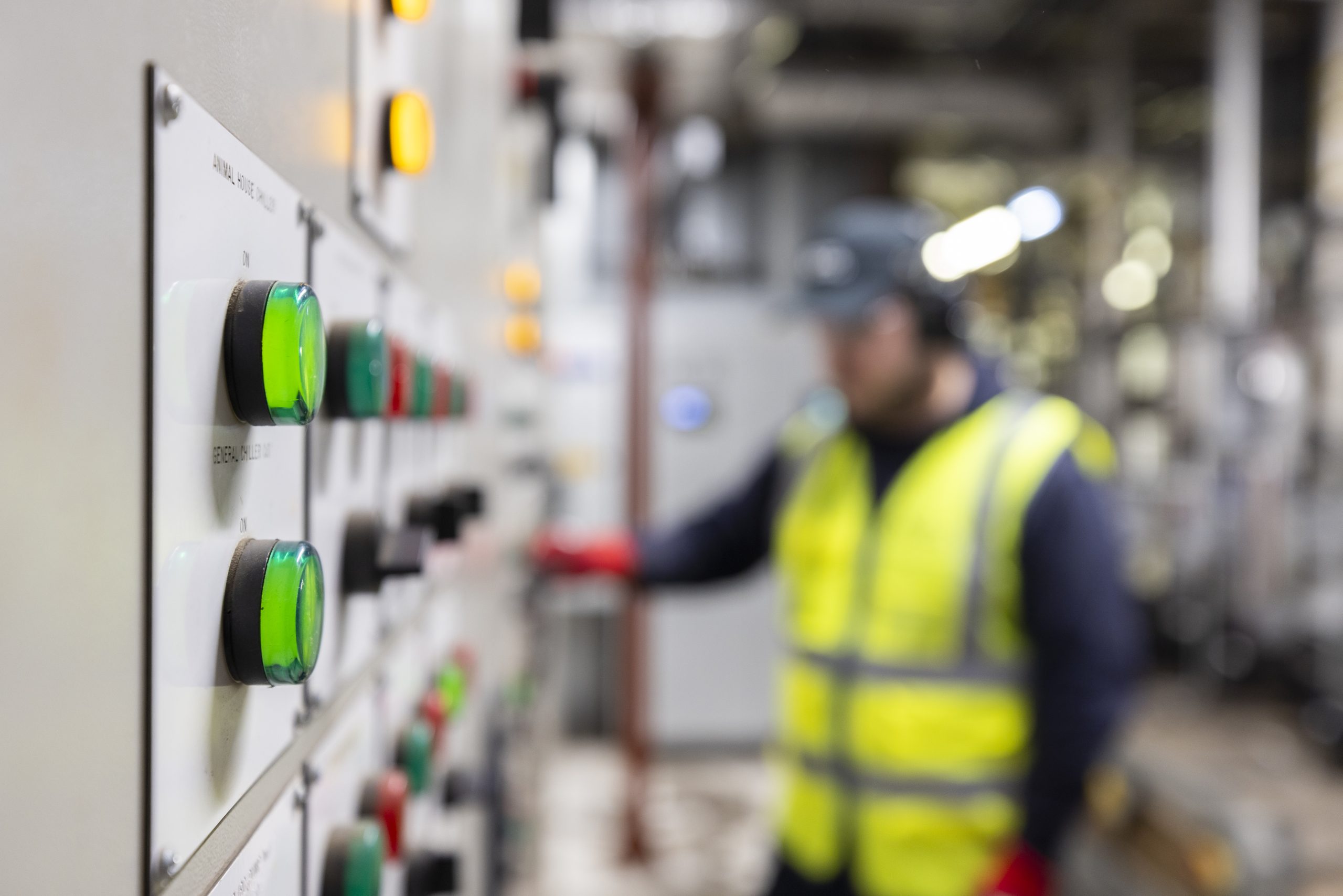 A close-up of a control panel with glowing green and orange buttons in a factory.